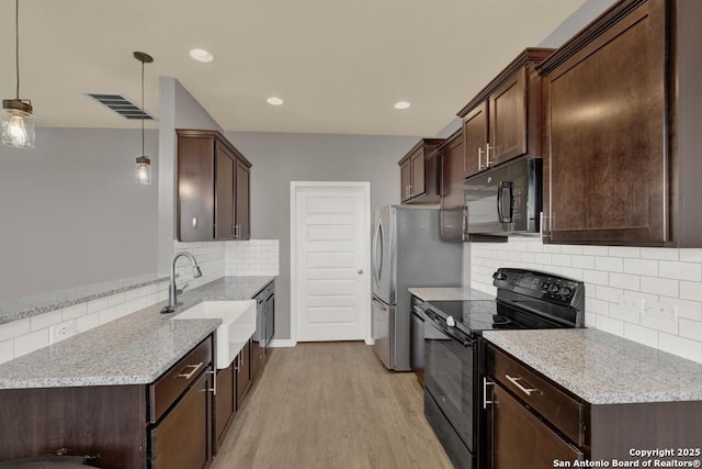 kitchen featuring visible vents, hanging light fixtures, a sink, dark brown cabinets, and black appliances