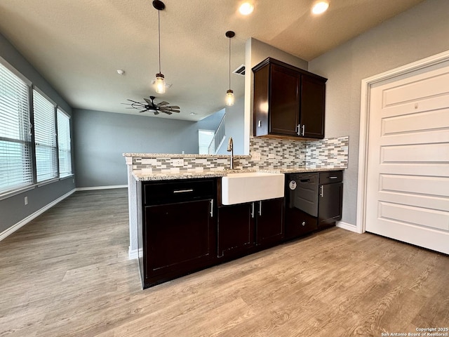 kitchen with decorative light fixtures, a sink, a peninsula, and decorative backsplash