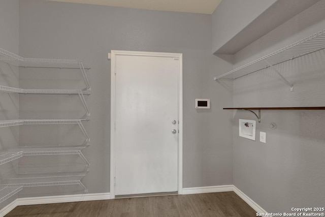 clothes washing area with baseboards, laundry area, wood finished floors, and hookup for a washing machine