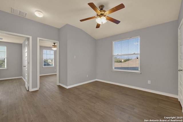 unfurnished room featuring lofted ceiling, ceiling fan, dark wood-type flooring, visible vents, and baseboards