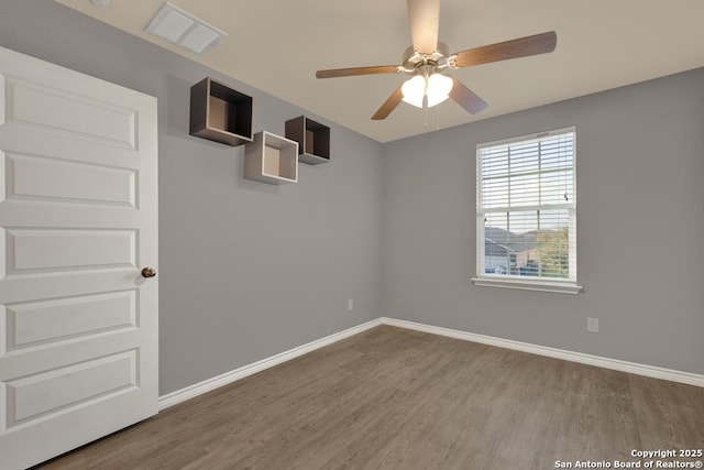 spare room with ceiling fan, wood finished floors, visible vents, and baseboards