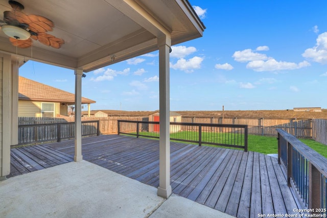 deck with a fenced backyard, a ceiling fan, and a yard