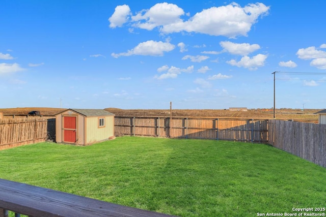 view of yard with an outbuilding, a fenced backyard, and a storage unit