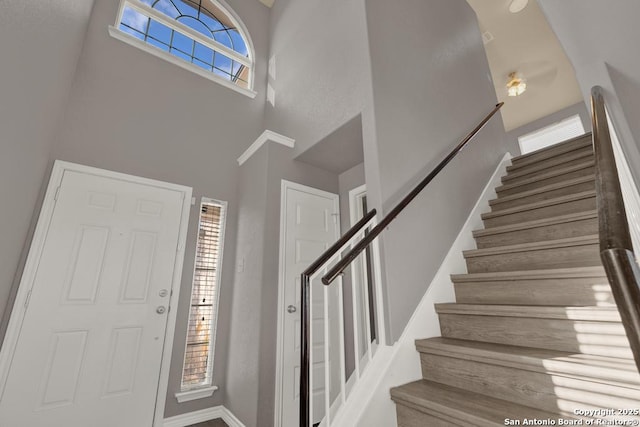 entryway featuring baseboards, stairway, and a high ceiling