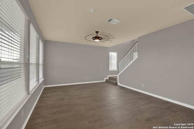 unfurnished room with baseboards, stairs, visible vents, and dark wood-style flooring