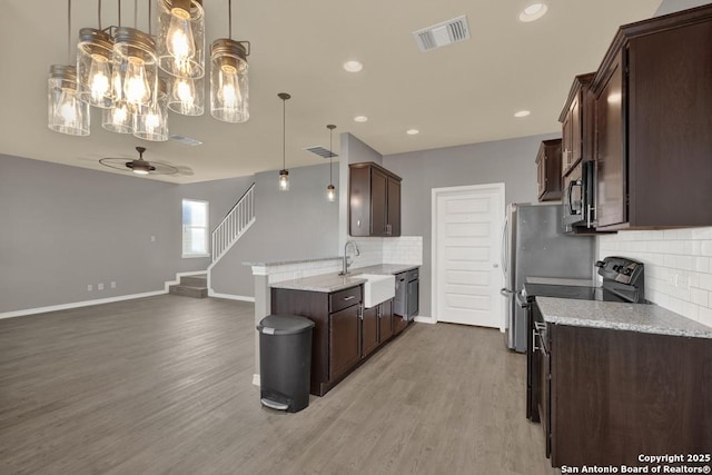 kitchen featuring light stone countertops, visible vents, hanging light fixtures, a sink, and wood finished floors