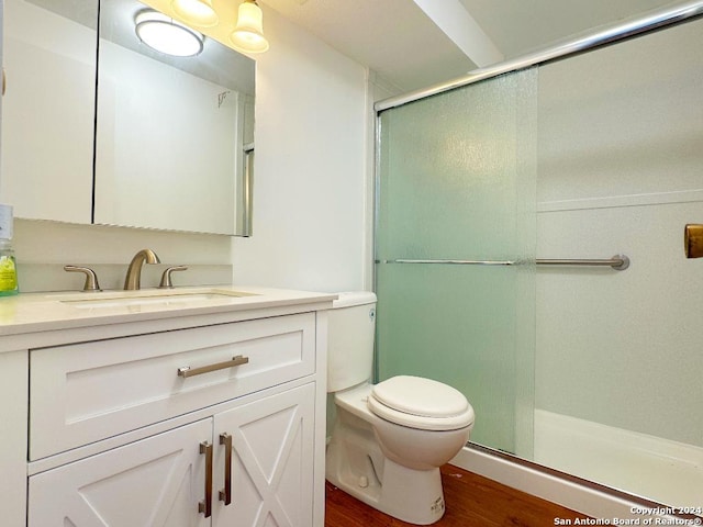 bathroom featuring hardwood / wood-style flooring, vanity, a shower with shower door, and toilet