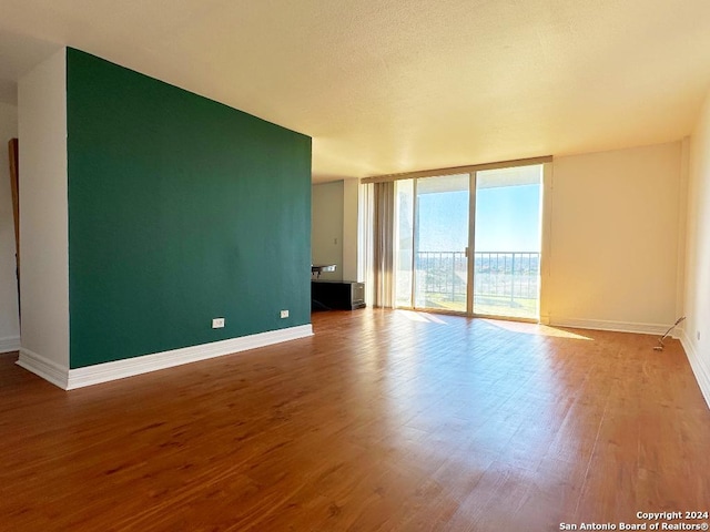 spare room featuring floor to ceiling windows and hardwood / wood-style flooring