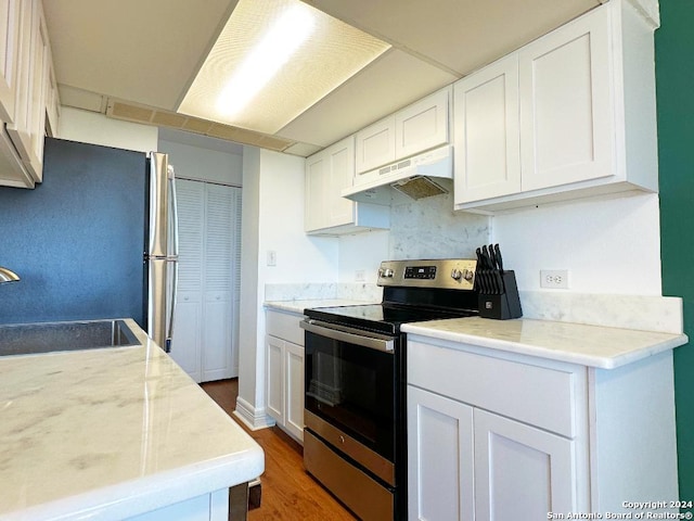 kitchen with light stone counters, stainless steel appliances, dark wood-type flooring, sink, and white cabinetry