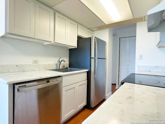 kitchen featuring white cabinets, sink, dark hardwood / wood-style floors, range hood, and appliances with stainless steel finishes