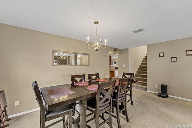 dining room with light carpet and a chandelier