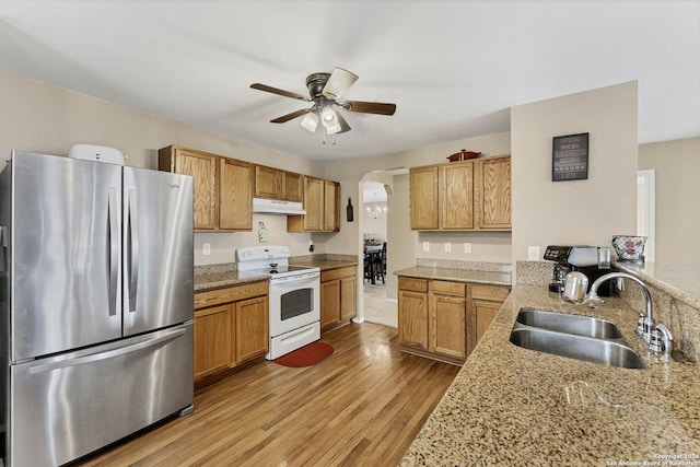 kitchen featuring sink, electric range, light hardwood / wood-style floors, light stone counters, and stainless steel refrigerator