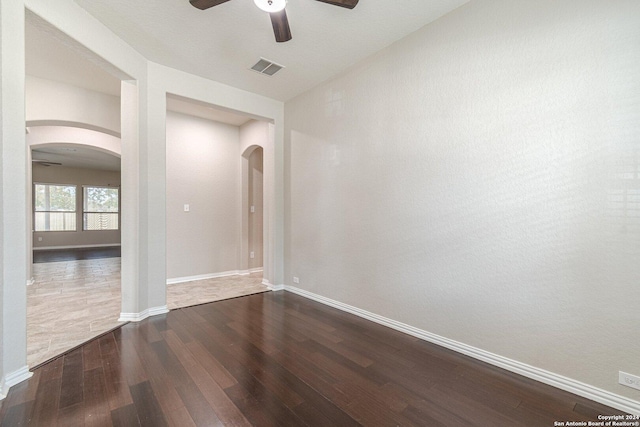 empty room with ceiling fan and dark wood-type flooring