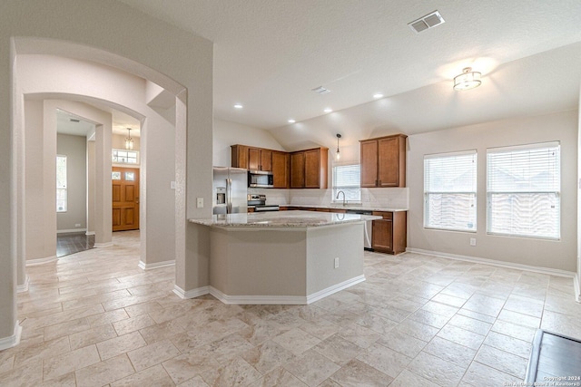 kitchen featuring sink, light stone counters, kitchen peninsula, vaulted ceiling, and appliances with stainless steel finishes