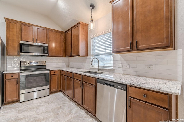 kitchen featuring pendant lighting, sink, vaulted ceiling, light stone countertops, and stainless steel appliances