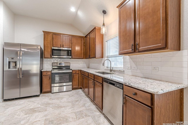 kitchen with light stone countertops, appliances with stainless steel finishes, vaulted ceiling, sink, and hanging light fixtures