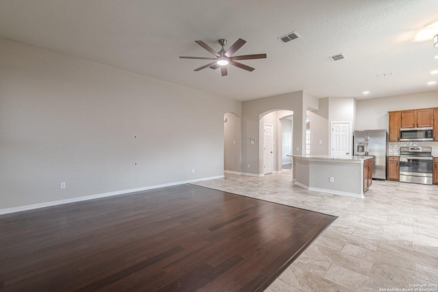 unfurnished living room featuring a textured ceiling and ceiling fan