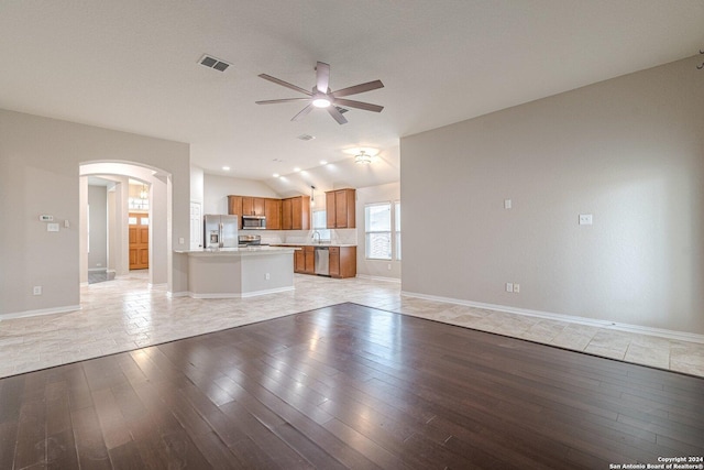 unfurnished living room featuring ceiling fan, vaulted ceiling, and light hardwood / wood-style flooring