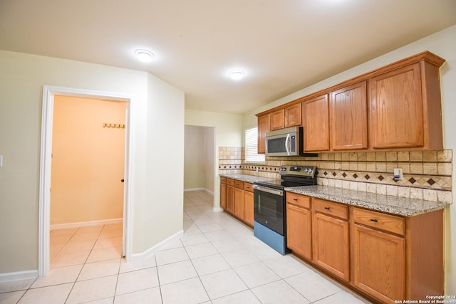 kitchen with light stone countertops, light tile patterned floors, stainless steel appliances, and tasteful backsplash