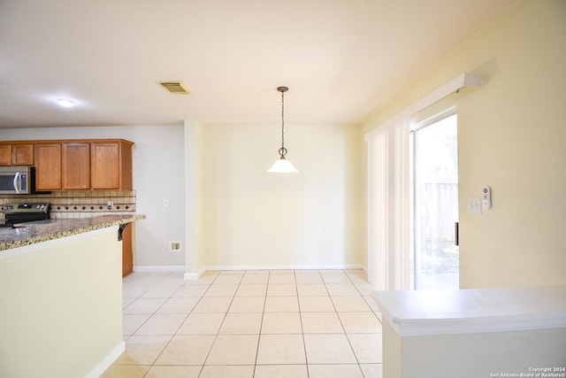 kitchen featuring stainless steel appliances, light stone counters, pendant lighting, decorative backsplash, and light tile patterned floors