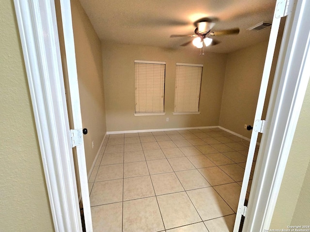 tiled empty room featuring ceiling fan