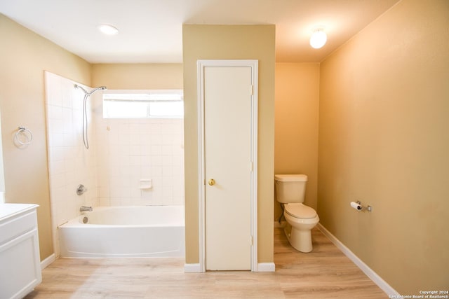 bathroom with hardwood / wood-style floors, toilet, and tiled shower / bath