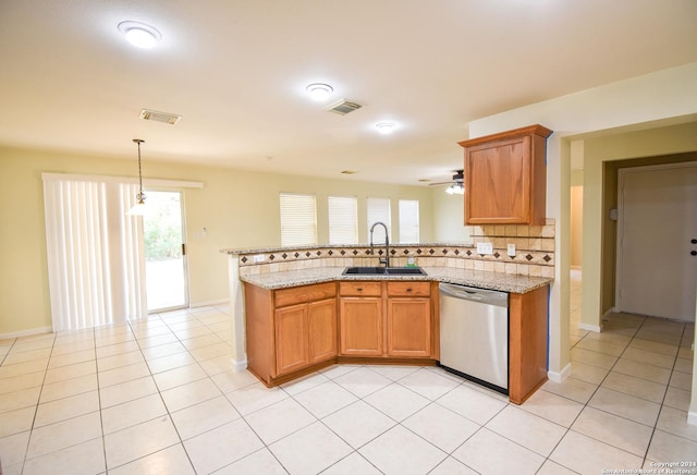 kitchen with dishwasher, sink, hanging light fixtures, light stone counters, and light tile patterned floors