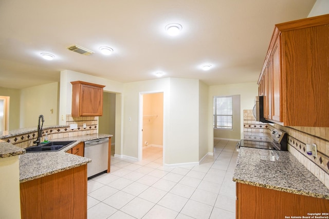 kitchen with sink, light stone counters, stainless steel dishwasher, stove, and decorative backsplash