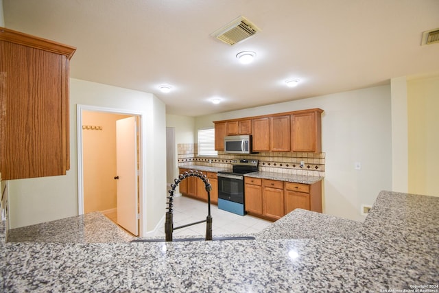 kitchen featuring backsplash, light stone counters, and appliances with stainless steel finishes