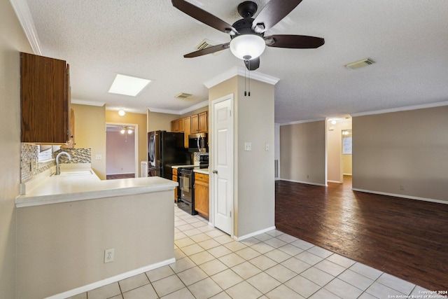 kitchen with crown molding, light tile patterned flooring, and black appliances