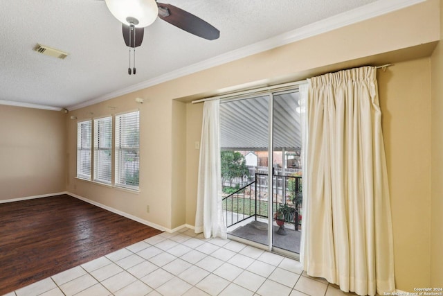 tiled empty room with a textured ceiling, ceiling fan, and crown molding