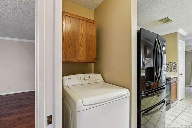 washroom featuring cabinets, crown molding, light tile patterned floors, a textured ceiling, and washer / clothes dryer