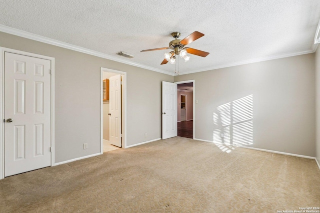 unfurnished bedroom featuring crown molding, ensuite bath, ceiling fan, a textured ceiling, and light colored carpet