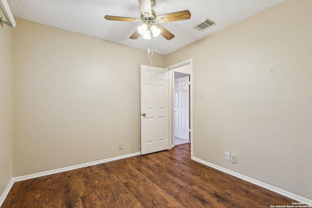 empty room with a textured ceiling, dark hardwood / wood-style flooring, and ceiling fan