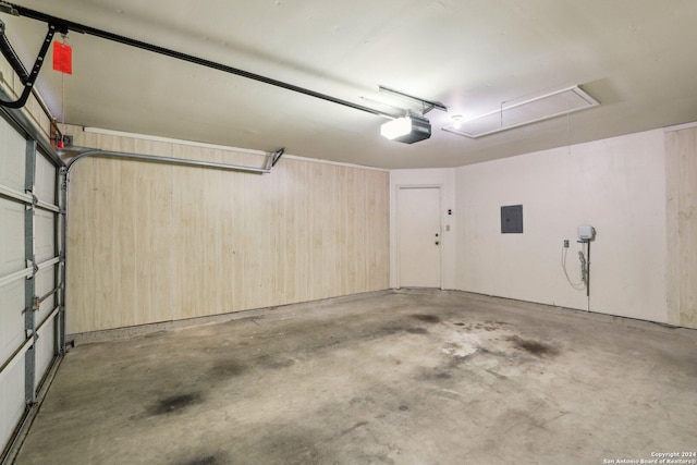 garage with wooden walls, electric panel, and a garage door opener