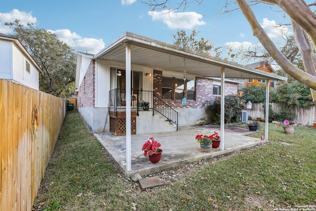 back of property with a lawn and a patio area