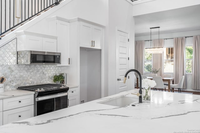 kitchen with light stone countertops, appliances with stainless steel finishes, pendant lighting, and sink