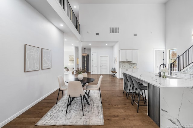 dining area with dark hardwood / wood-style flooring and a towering ceiling