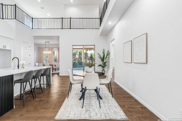 dining space featuring dark hardwood / wood-style flooring, a towering ceiling, and sink