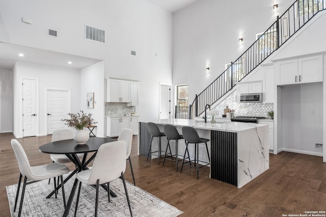 dining room featuring sink, dark wood-type flooring, and a high ceiling