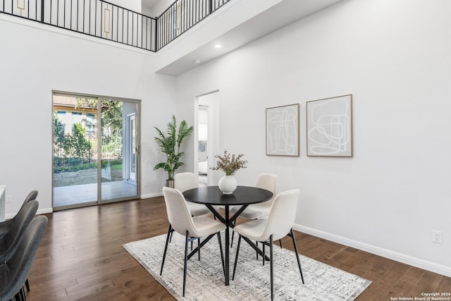 dining area with dark hardwood / wood-style flooring and a high ceiling