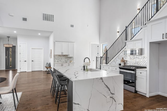 kitchen featuring a center island with sink, white cabinetry, stainless steel appliances, and tasteful backsplash