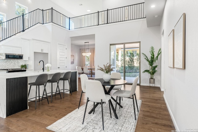 dining room with sink, a towering ceiling, dark hardwood / wood-style floors, and an inviting chandelier