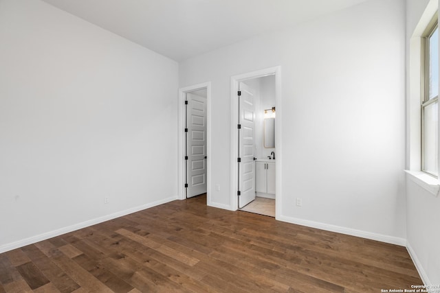 unfurnished bedroom with dark hardwood / wood-style flooring and ensuite bath