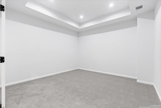 carpeted empty room with a tray ceiling