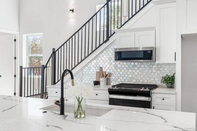 kitchen featuring white cabinetry, light stone countertops, sink, and appliances with stainless steel finishes