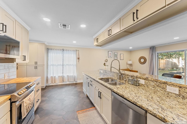 kitchen with light stone countertops, appliances with stainless steel finishes, crown molding, and sink