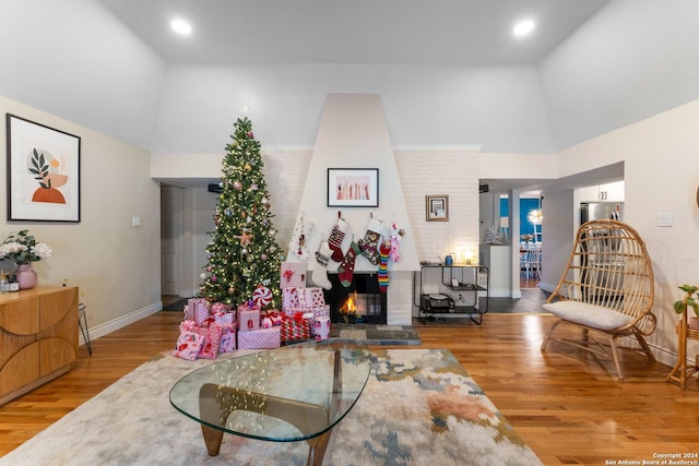 living room with high vaulted ceiling, wood-type flooring, and a brick fireplace