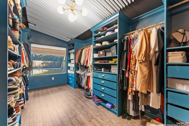 spacious closet featuring hardwood / wood-style floors, lofted ceiling, and a notable chandelier