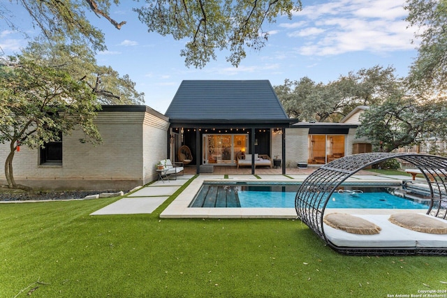 back of house featuring an outbuilding, a patio area, and a lawn